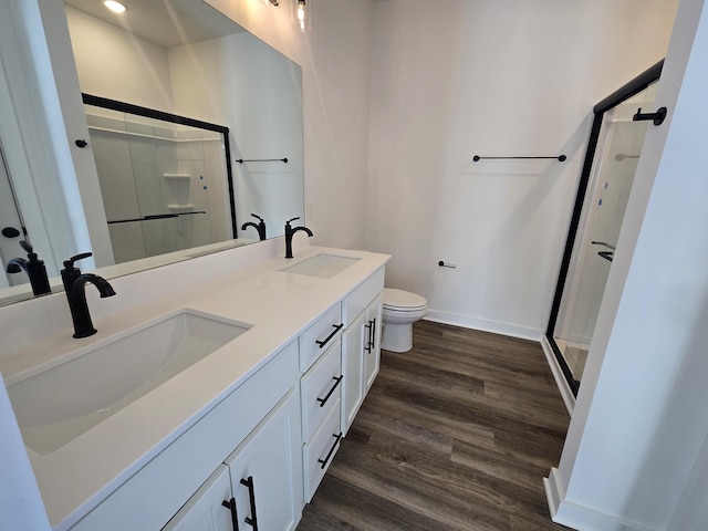 bathroom with an enclosed shower, vanity, wood-type flooring, and toilet