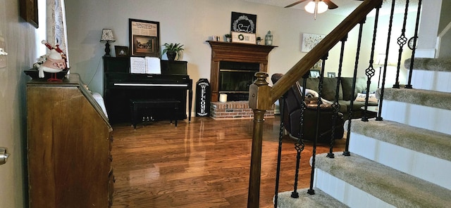 staircase featuring hardwood / wood-style floors, ceiling fan, and a fireplace