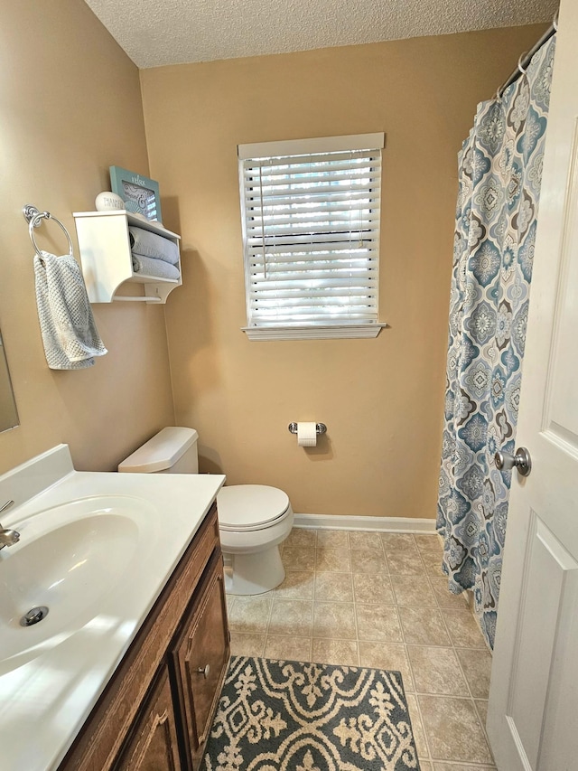 bathroom with tile patterned floors, vanity, a textured ceiling, and toilet