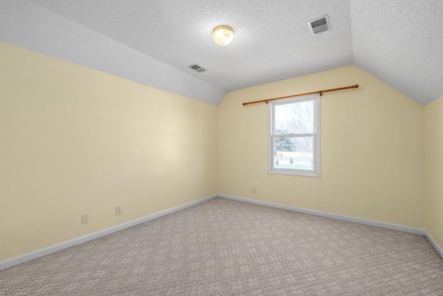 empty room with vaulted ceiling, carpet floors, and a textured ceiling