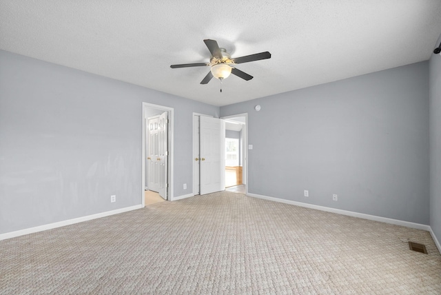 unfurnished bedroom with ceiling fan, light colored carpet, connected bathroom, and a textured ceiling