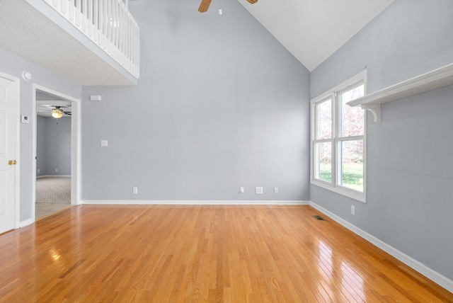 empty room featuring ceiling fan, high vaulted ceiling, and light hardwood / wood-style flooring