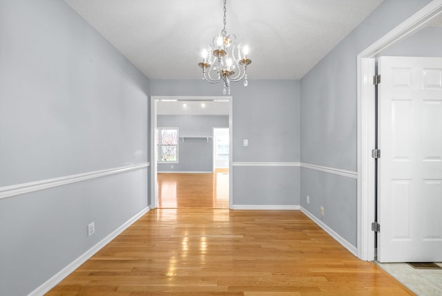 unfurnished dining area featuring a notable chandelier and light hardwood / wood-style flooring