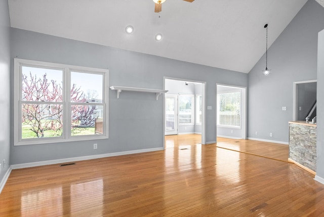 unfurnished living room with ceiling fan, high vaulted ceiling, and light hardwood / wood-style flooring