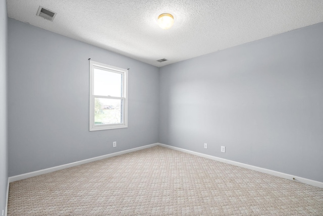 empty room with light carpet and a textured ceiling