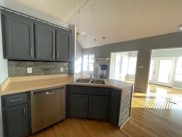 kitchen featuring lofted ceiling, sink, stainless steel dishwasher, ceiling fan, and kitchen peninsula