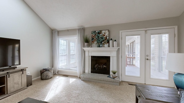 carpeted living room with a fireplace, french doors, and vaulted ceiling