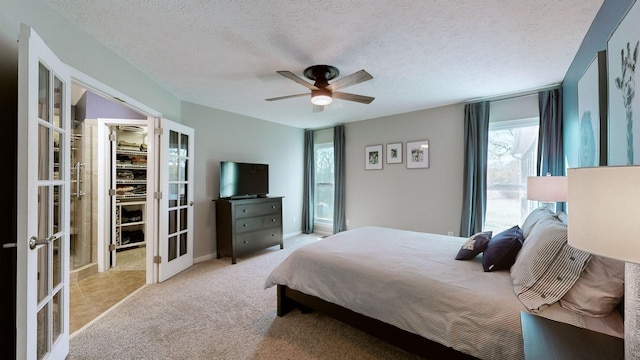 bedroom with light carpet, french doors, ceiling fan, a spacious closet, and a textured ceiling