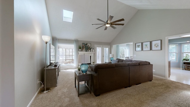 living room featuring light carpet, a skylight, high vaulted ceiling, and a wealth of natural light