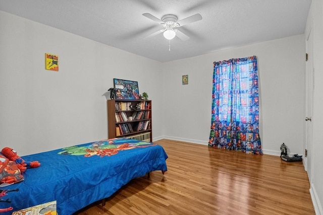 bedroom featuring ceiling fan, wood-type flooring, and a textured ceiling