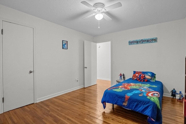 bedroom with ceiling fan, wood-type flooring, and a textured ceiling