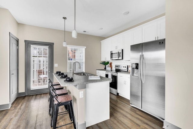 kitchen with stainless steel appliances, sink, dark hardwood / wood-style floors, white cabinetry, and hanging light fixtures