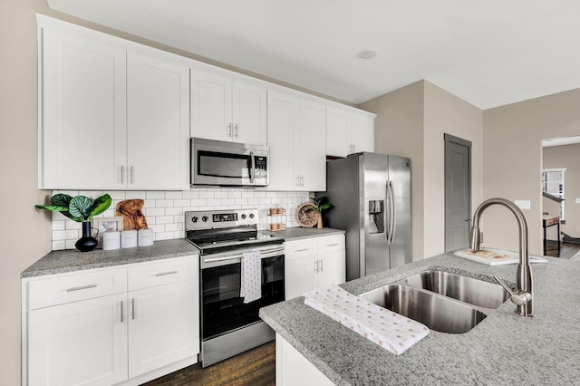 kitchen featuring tasteful backsplash, white cabinetry, sink, and appliances with stainless steel finishes