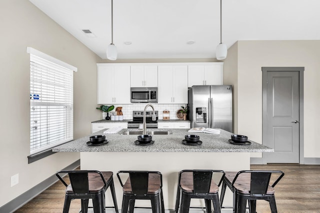 kitchen with stainless steel appliances, hanging light fixtures, a center island with sink, and sink