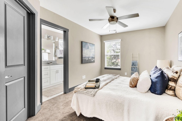 bedroom featuring light colored carpet, ensuite bath, ceiling fan, and sink