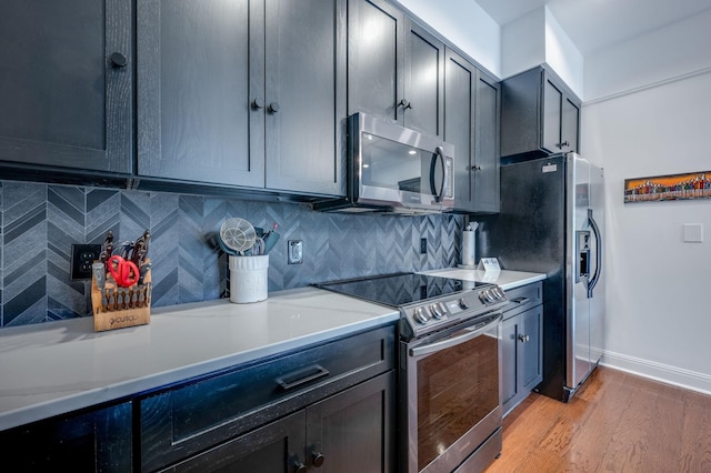 kitchen with appliances with stainless steel finishes, tasteful backsplash, and light hardwood / wood-style flooring