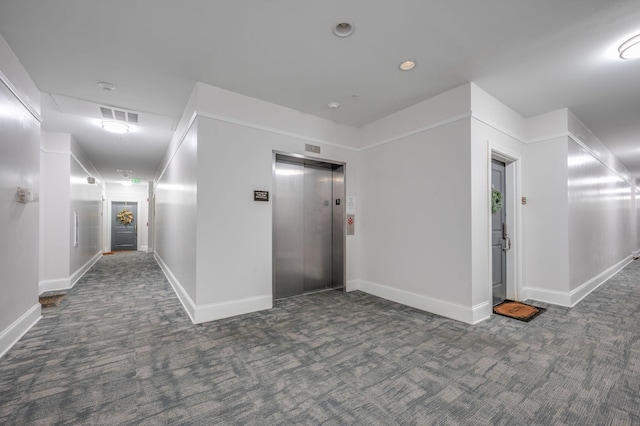 corridor with elevator and dark carpet