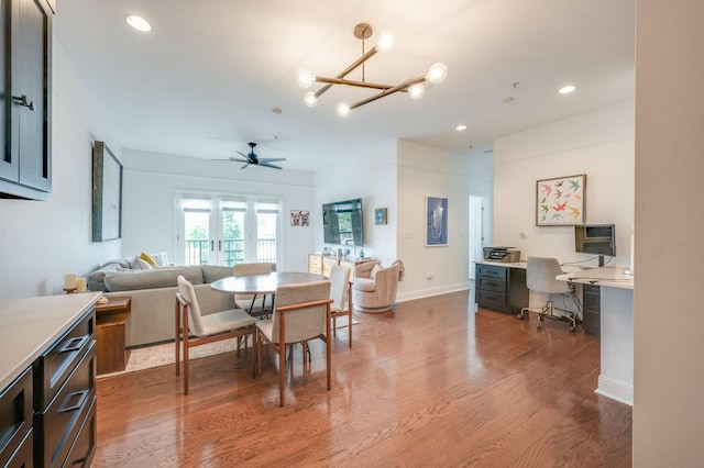 dining room with hardwood / wood-style flooring and ceiling fan with notable chandelier