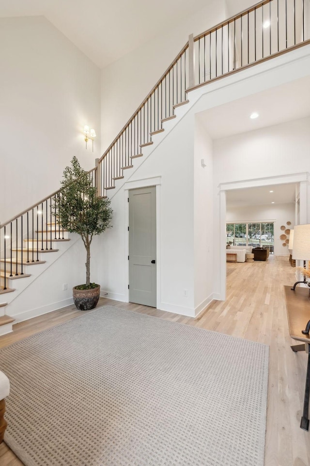 foyer with stairway, wood finished floors, a high ceiling, and baseboards