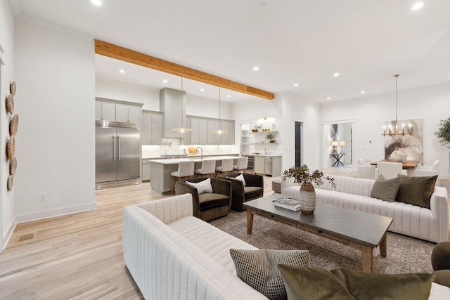 living room with beam ceiling, light wood-style flooring, a notable chandelier, and recessed lighting