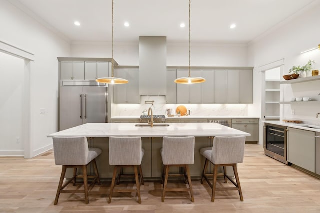 kitchen with range hood, beverage cooler, light wood finished floors, stainless steel built in fridge, and crown molding