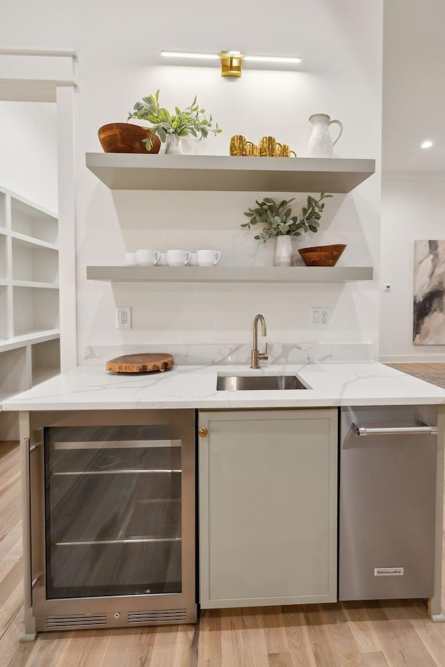 bar with stainless steel dishwasher, wine cooler, light wood finished floors, and a sink