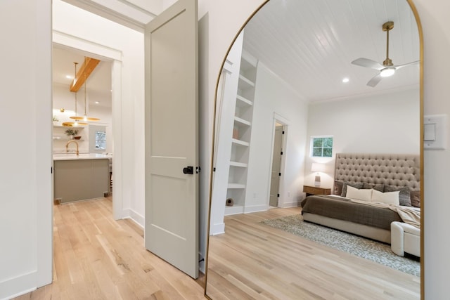 bedroom featuring baseboards, light wood-type flooring, recessed lighting, ensuite bath, and a sink