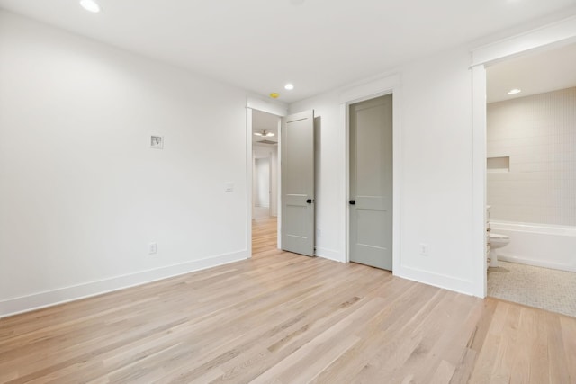 unfurnished bedroom with recessed lighting, baseboards, light wood-style flooring, and ensuite bathroom