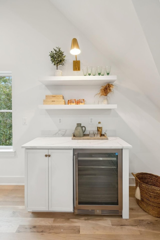 bar featuring wine cooler, light wood finished floors, baseboards, and a dry bar