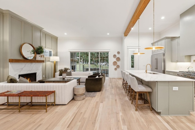 living room with beamed ceiling, recessed lighting, a fireplace, and light wood-type flooring