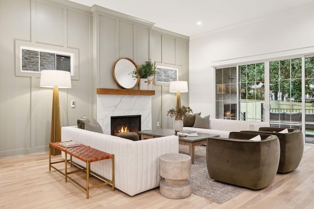 living room with a decorative wall, light wood-style flooring, and a high end fireplace