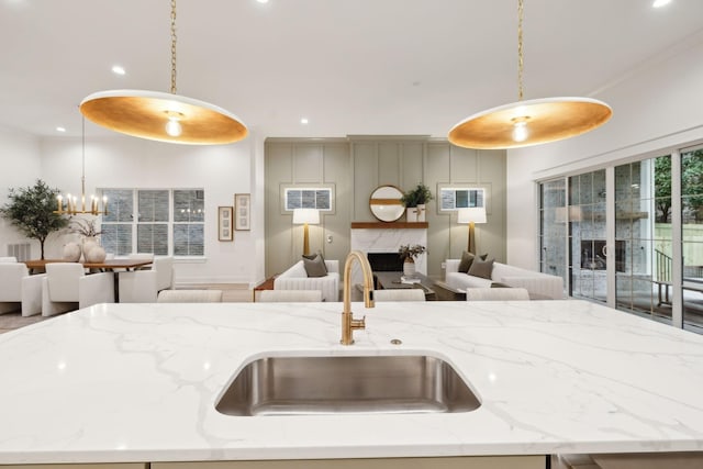 kitchen with hanging light fixtures, open floor plan, a kitchen island with sink, and a sink