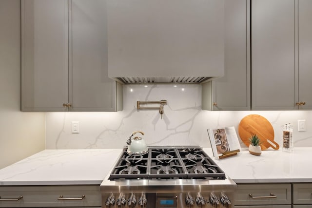 kitchen featuring range, tasteful backsplash, custom exhaust hood, and gray cabinets