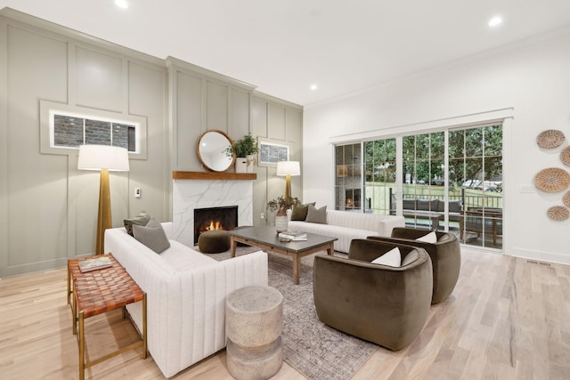 living area with recessed lighting, baseboards, light wood-style floors, and a high end fireplace