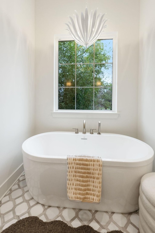 bathroom featuring tile patterned floors, baseboards, and a freestanding bath