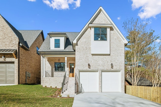 view of front of property featuring a porch, fence, concrete driveway, a front yard, and brick siding