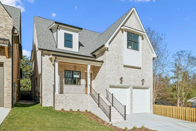 view of front of house featuring brick siding, a front lawn, concrete driveway, covered porch, and an attached garage