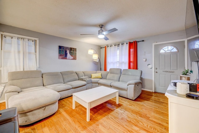 living room featuring hardwood / wood-style flooring, ceiling fan, and a textured ceiling