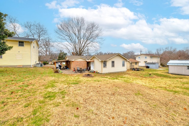 rear view of property with a yard, central AC unit, and a storage unit