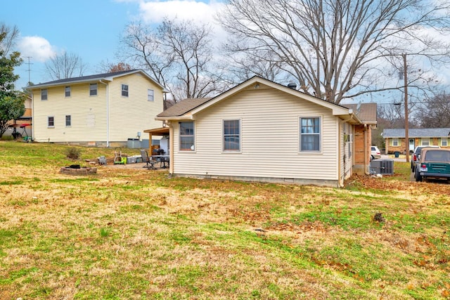 back of property with an outdoor fire pit, crawl space, cooling unit, and a lawn