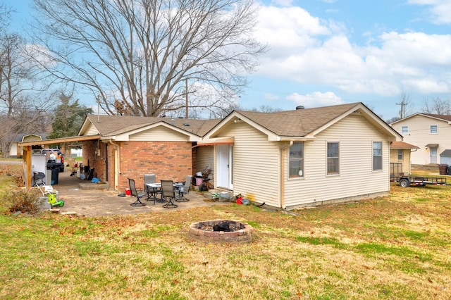 back of property with a patio area, brick siding, a lawn, and a fire pit