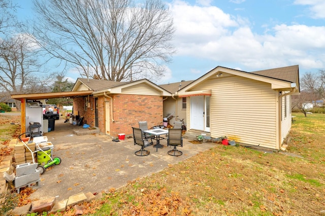 back of property featuring an attached carport, brick siding, and a yard