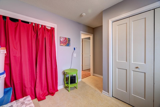 rec room with light carpet, a textured ceiling, and baseboards