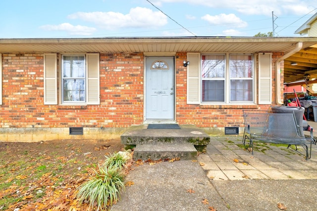 doorway to property with crawl space and brick siding