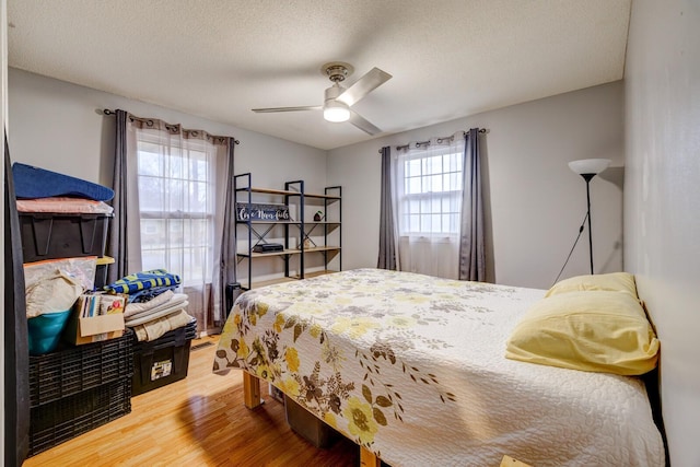 bedroom with ceiling fan, a textured ceiling, and wood finished floors