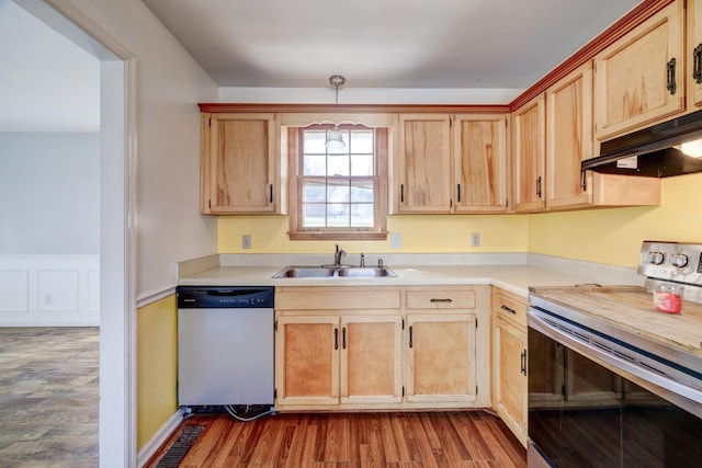 kitchen featuring light brown cabinets, wood finished floors, a sink, light countertops, and appliances with stainless steel finishes