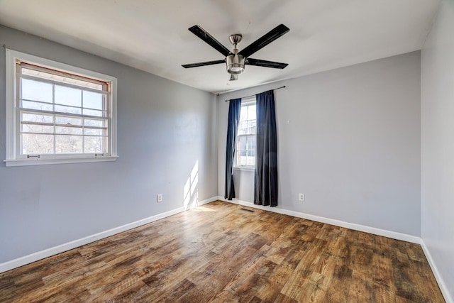 unfurnished room with a ceiling fan, visible vents, baseboards, and wood finished floors