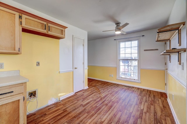 interior space featuring ceiling fan, light countertops, wood finished floors, and light brown cabinets