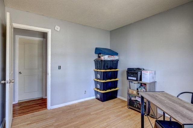 office featuring a textured ceiling, light wood-style flooring, and baseboards