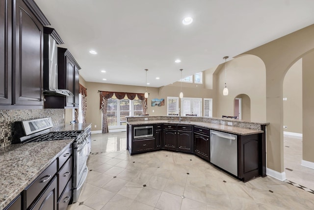 kitchen featuring light stone counters, decorative backsplash, stainless steel appliances, and decorative light fixtures